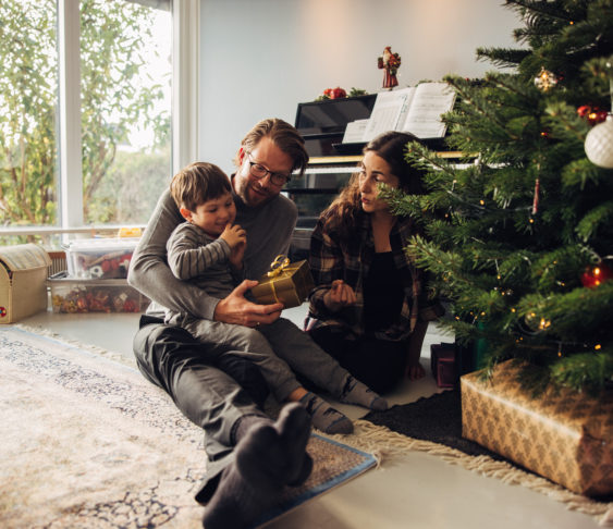 Family sitting on the floor next to their Christmas tree