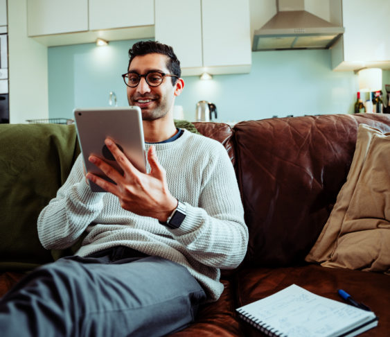 Man sitting on couch using his tablet