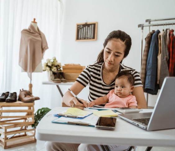 Image of a woman sitting with a baby on her lap in front of a laptop