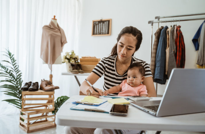 Image of a woman sitting with a baby on her lap in front of a laptop